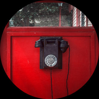 Inside of old telephone booth with red background and black public phone